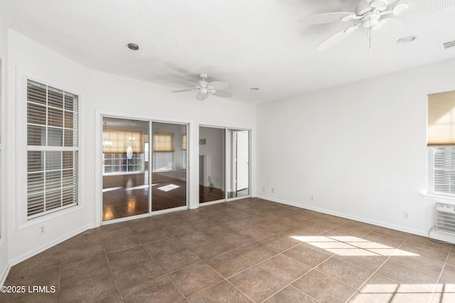 unfurnished room featuring visible vents, a textured ceiling, baseboards, and ceiling fan