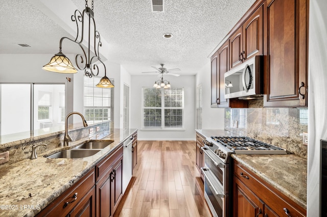 kitchen with visible vents, light wood-type flooring, decorative backsplash, appliances with stainless steel finishes, and a sink