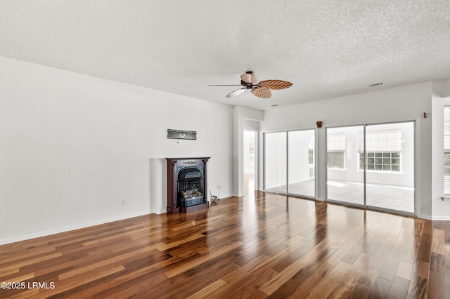 unfurnished living room with wood finished floors, baseboards, visible vents, ceiling fan, and a textured ceiling