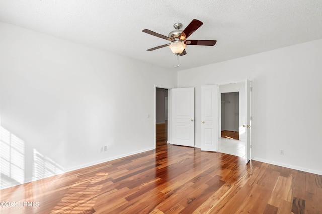 unfurnished bedroom featuring ceiling fan, baseboards, a textured ceiling, and wood finished floors