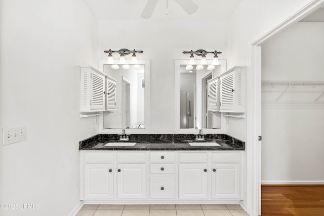 bathroom featuring double vanity, a walk in closet, a ceiling fan, and a sink