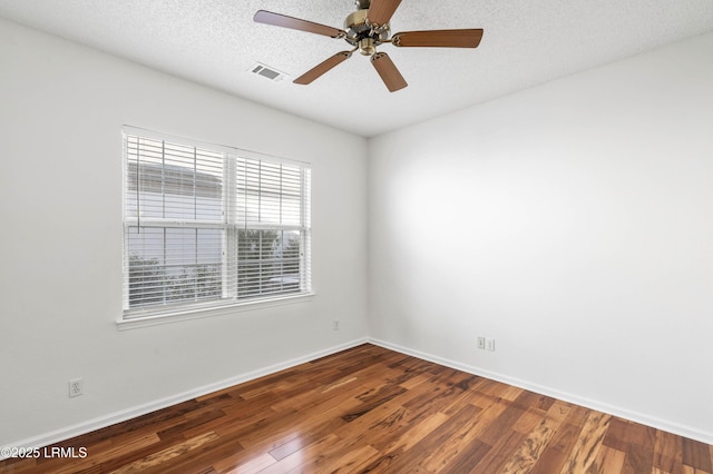 spare room featuring visible vents, a textured ceiling, baseboards, and wood finished floors