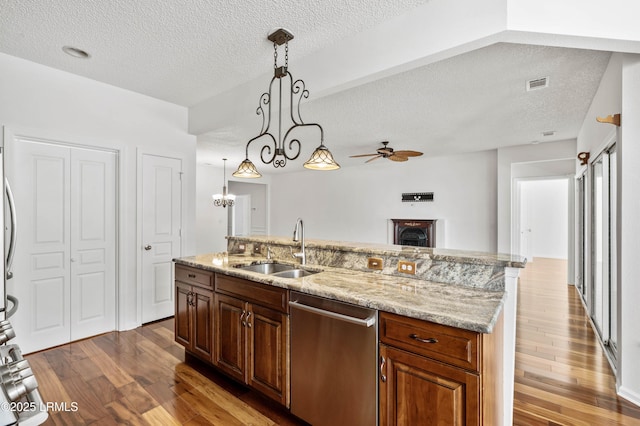 kitchen featuring a sink, stainless steel dishwasher, an island with sink, and wood finished floors