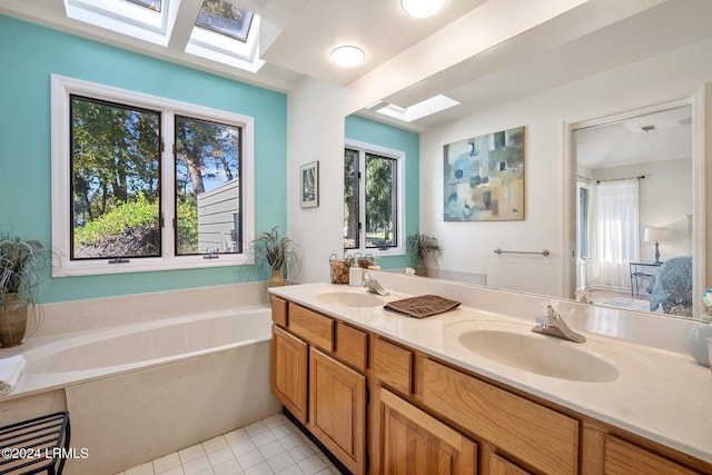 bathroom featuring tile patterned flooring, vanity, a bathing tub, and a skylight