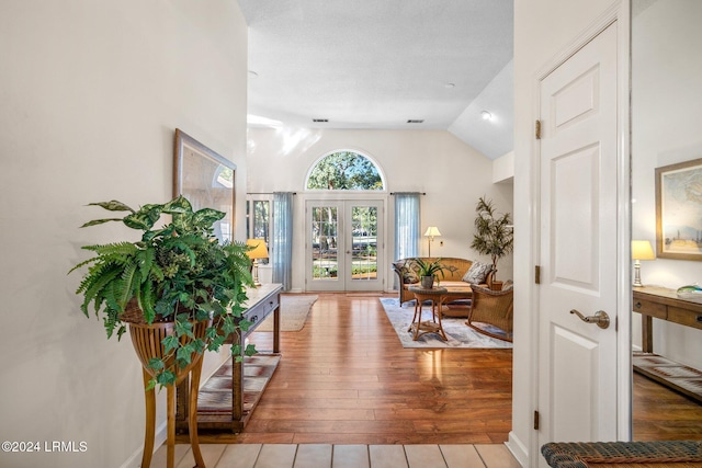 entrance foyer with lofted ceiling, light hardwood / wood-style floors, and french doors