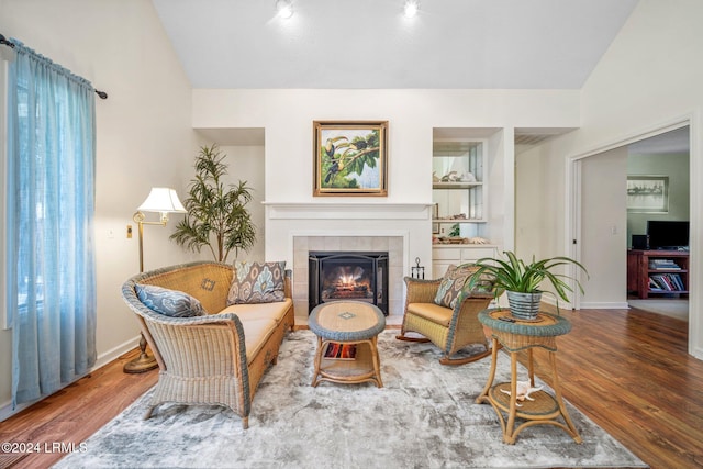 living area featuring built in features, wood-type flooring, and a tile fireplace