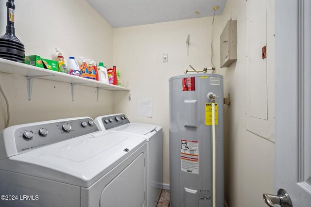 clothes washing area with water heater, washer and dryer, and a textured ceiling