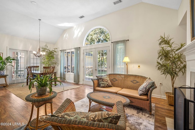 living room featuring vaulted ceiling, dark wood-type flooring, a notable chandelier, and french doors