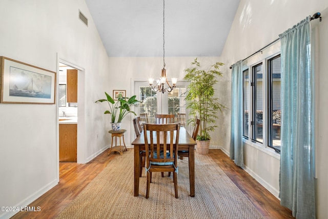 dining space with hardwood / wood-style flooring, lofted ceiling, and a chandelier