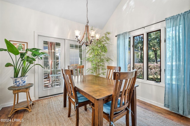 dining room with hardwood / wood-style flooring, a chandelier, vaulted ceiling, and french doors