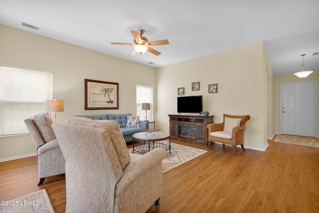living area featuring a ceiling fan, baseboards, visible vents, and light wood-style flooring