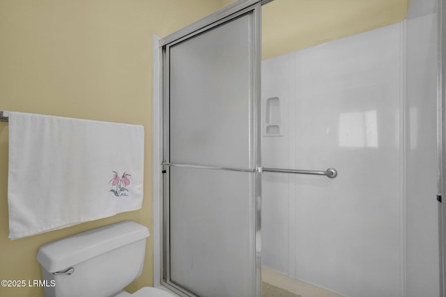 bathroom featuring toilet and a shower with shower door