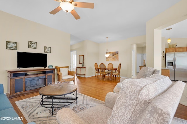 living room featuring light wood-style floors, baseboards, and ceiling fan