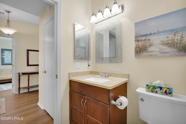 ensuite bathroom featuring visible vents, wood finished floors, vanity, toilet, and ensuite bathroom