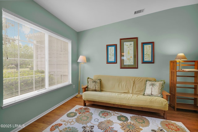 living area with visible vents, baseboards, wood finished floors, and a wealth of natural light