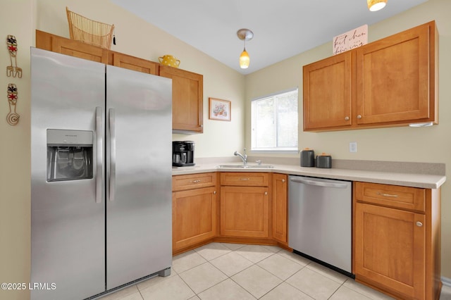 kitchen with brown cabinetry, light countertops, a sink, appliances with stainless steel finishes, and light tile patterned floors