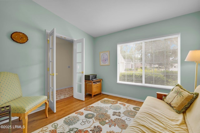 sitting room featuring baseboards, french doors, and wood finished floors