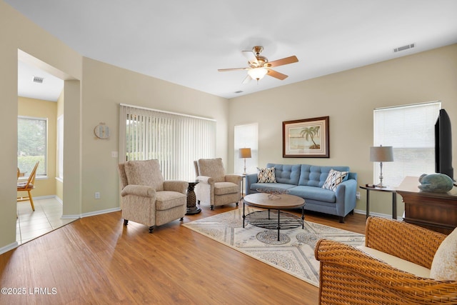living area with baseboards, ceiling fan, light wood-type flooring, and visible vents