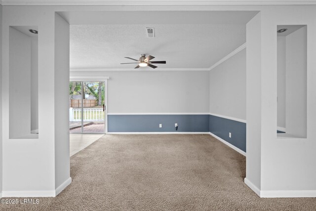 spare room with carpet, a ceiling fan, baseboards, visible vents, and ornamental molding