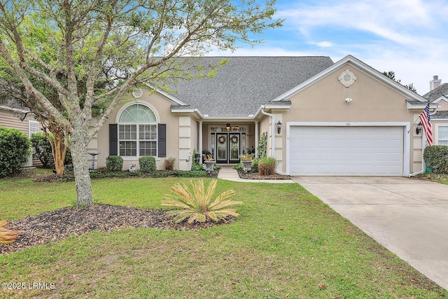 128 Colvin Dr, Okatie, SC 29909 - ranch-style house with a front yard, an attached garage, concrete driveway, stucco siding, and roof with shingles