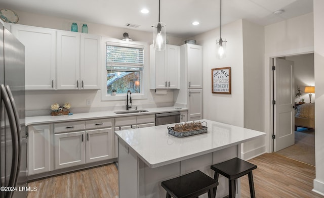 kitchen with a kitchen bar, sink, white cabinetry, light wood-type flooring, and stainless steel appliances