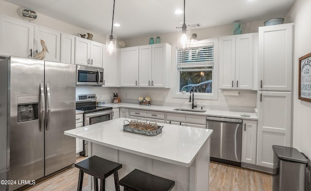 kitchen featuring appliances with stainless steel finishes, decorative light fixtures, sink, and white cabinets