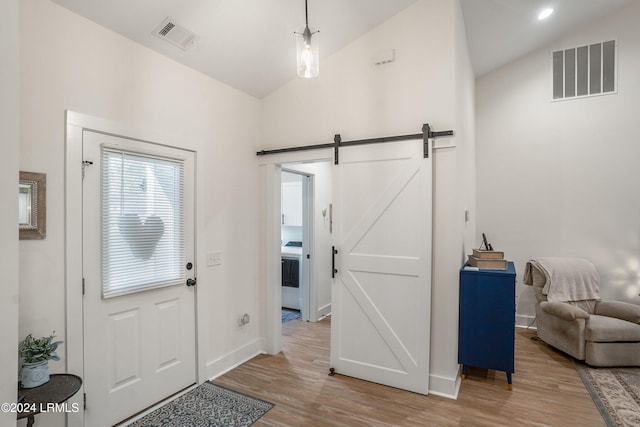 entryway with lofted ceiling, hardwood / wood-style floors, and a barn door