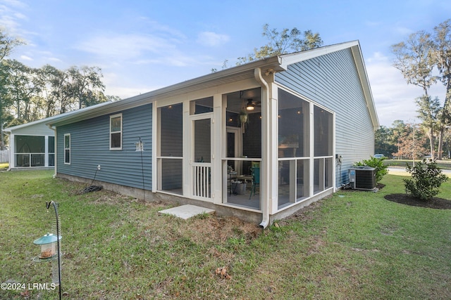 back of property featuring a sunroom, cooling unit, and a lawn