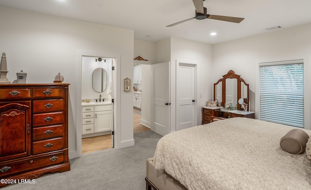 bedroom with sink, ensuite bath, light colored carpet, and ceiling fan