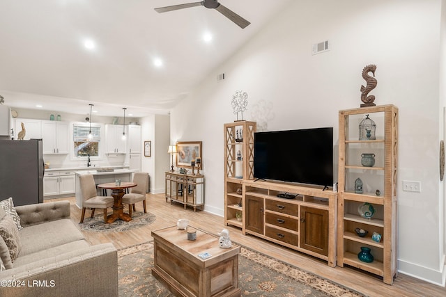 living room with ceiling fan, high vaulted ceiling, light hardwood / wood-style floors, and sink