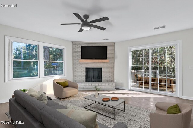 living room featuring ceiling fan, hardwood / wood-style floors, and a brick fireplace