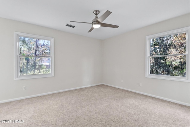 spare room with a wealth of natural light, ceiling fan, and carpet