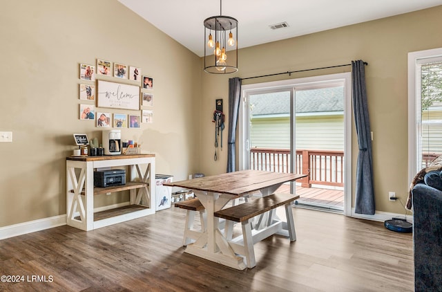 dining space with vaulted ceiling, a healthy amount of sunlight, and hardwood / wood-style floors