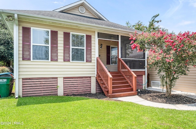 view of front of home featuring crawl space, a shingled roof, a front yard, and a sunroom