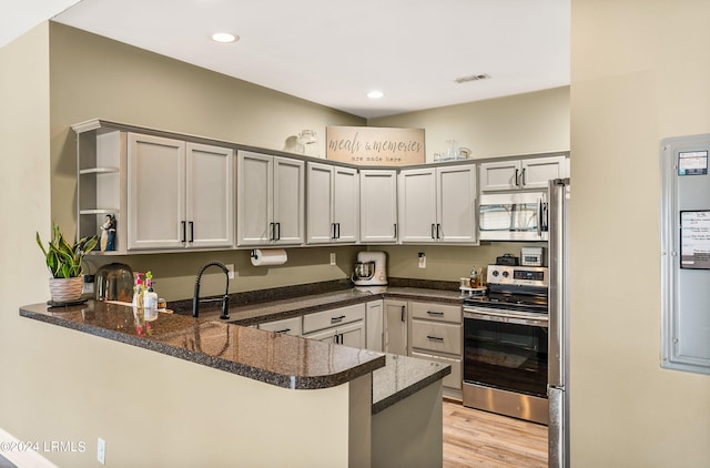 kitchen featuring sink, light hardwood / wood-style flooring, appliances with stainless steel finishes, dark stone countertops, and kitchen peninsula