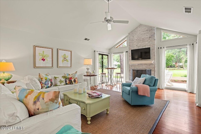 living room featuring a brick fireplace, hardwood / wood-style flooring, a healthy amount of sunlight, and ceiling fan