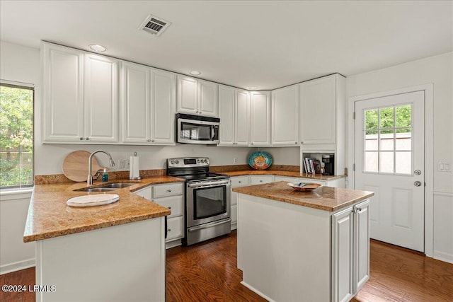 kitchen with sink, stainless steel appliances, light stone counters, white cabinets, and kitchen peninsula