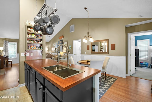 kitchen with pendant lighting, black dishwasher, sink, a notable chandelier, and light hardwood / wood-style floors