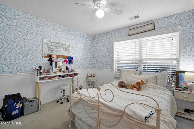 carpeted bedroom featuring ceiling fan and a textured ceiling