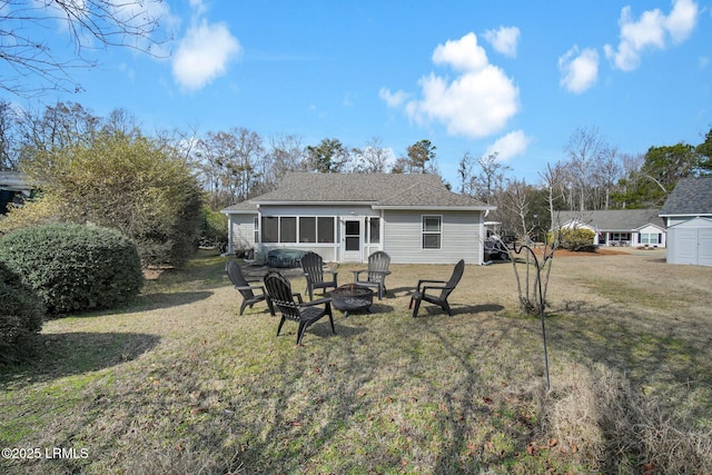 rear view of property featuring an outdoor fire pit and a lawn