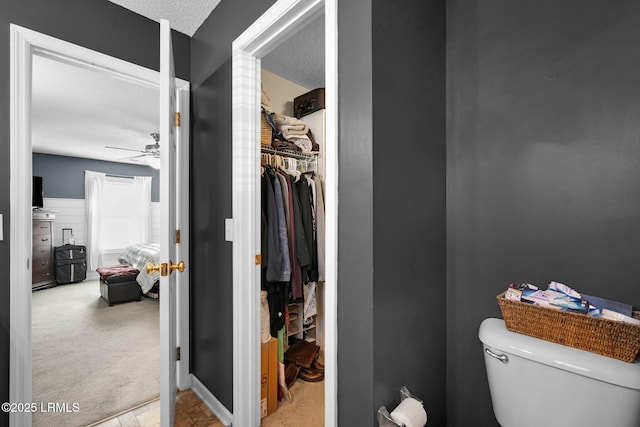 bathroom featuring ceiling fan, toilet, and a textured ceiling