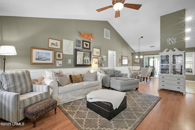 living room with ceiling fan, wood-type flooring, and high vaulted ceiling