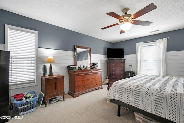 bedroom with light carpet, ceiling fan, and a textured ceiling