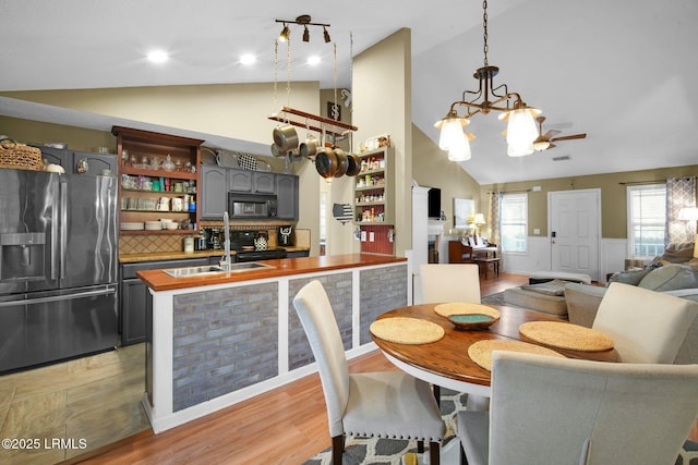 dining room featuring plenty of natural light, a notable chandelier, high vaulted ceiling, and light hardwood / wood-style flooring