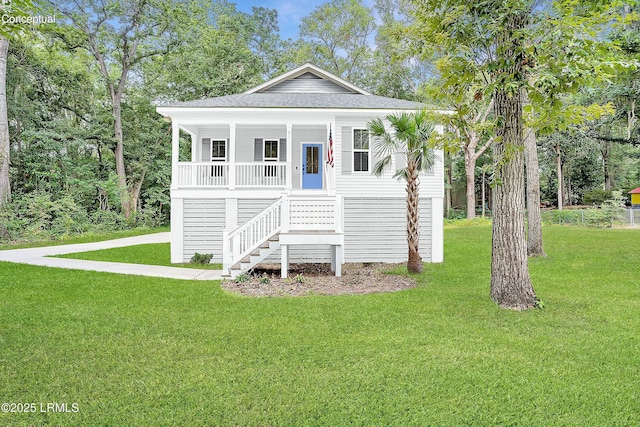 coastal home with stairway, covered porch, a front yard, and roof with shingles