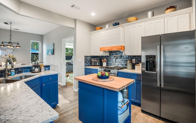 kitchen featuring blue cabinets, sink, a center island, stainless steel appliances, and white cabinets