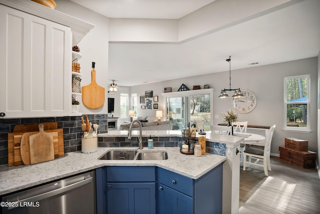 kitchen with sink, blue cabinetry, dishwasher, backsplash, and light stone countertops