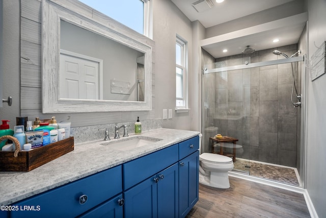 bathroom with hardwood / wood-style flooring, vanity, toilet, and a shower with shower door