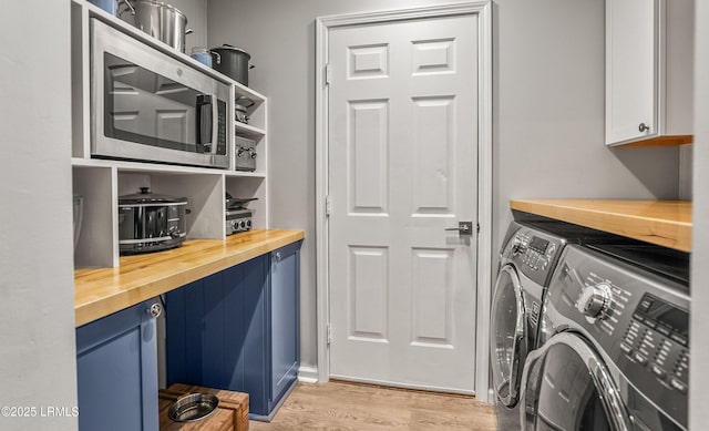 washroom with cabinets, washer and dryer, and light hardwood / wood-style floors