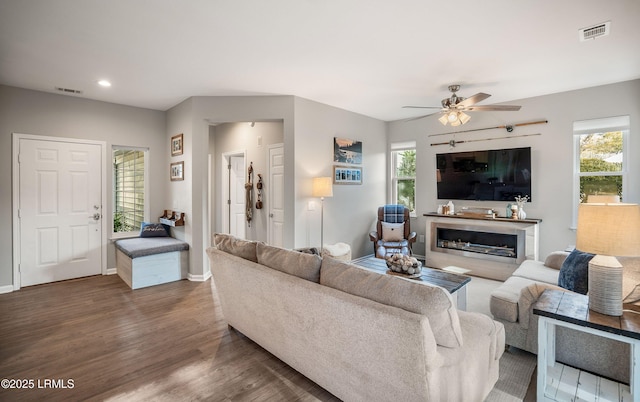 living room with dark wood-type flooring, a wealth of natural light, and ceiling fan